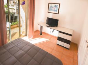 a bedroom with a bed and a desk with a television at Orangeraie du Cap d'Antibes in Antibes