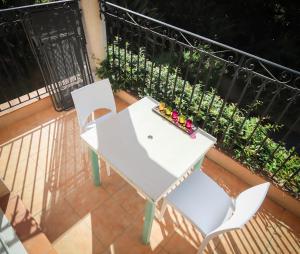 d'une table blanche et de deux chaises sur un balcon. dans l'établissement Orangeraie du Cap d'Antibes, à Antibes