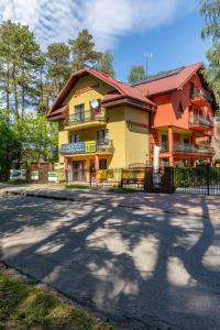 a yellow and orange building with a fence next to a street at Panorama in Pobierowo
