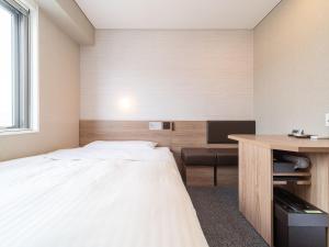 a hotel room with a bed and a desk at Super Hotel Higashi-Maizuru in Maizuru