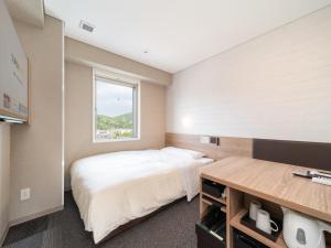 a small bedroom with a bed and a window at Super Hotel Higashi-Maizuru in Maizuru
