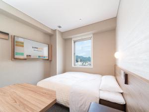 a small bedroom with a bed and a window at Super Hotel Higashi-Maizuru in Maizuru