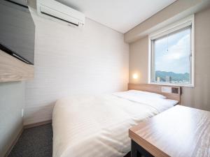 two beds in a room with a window at Super Hotel Higashi-Maizuru in Maizuru