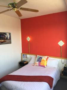 a bedroom with a large bed with a red wall at Arche Hotel in Vierzon
