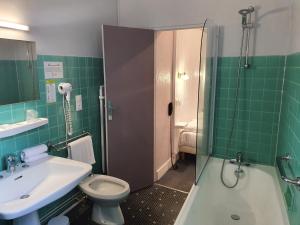 a bathroom with a toilet, sink, and shower at Hotel De France in Perpignan