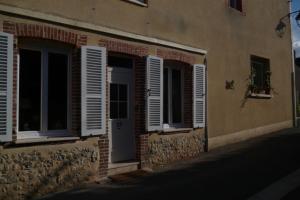 un edificio con ventanas con persianas y una puerta en Le Relais de Montigny, en Montigny-le-Gannelon