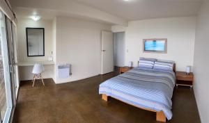 a bedroom with a bed with blue and white sheets at Mukies Apartments in Ahipara