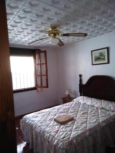 une chambre avec un lit et un ventilateur de plafond dans l'établissement El Carmen, à Cazalla de la Sierra 5 autres photos