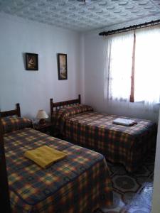 une chambre d'hôtel avec deux lits et une fenêtre dans l'établissement El Carmen, à Cazalla de la Sierra