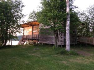 eine Blockhütte mit einer Veranda und einem Baum in der Unterkunft Kyly in Savonlinna