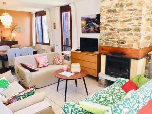 a living room with couches and a stone fireplace at Gaou Benat, village des fourches, Label patrimoine XXe siècle in Bormes-les-Mimosas