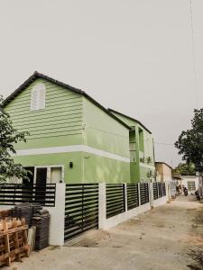 a green building with a fence in front of it at Nhiên Homestay - The Green House in Phú Quốc