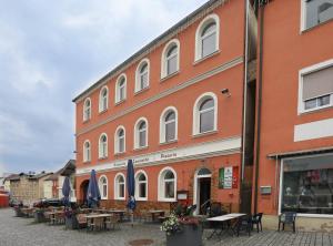 ein großes Gebäude mit Tischen und Stühlen davor in der Unterkunft Pension Leonardo in Aidenbach