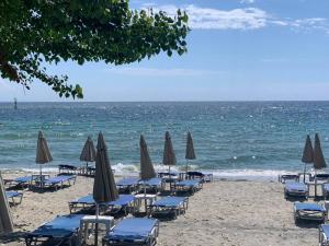 einen Strand mit Liegestühlen und Sonnenschirmen und dem Meer in der Unterkunft VILLA HARIKLIA in Paralia Katerinis