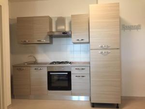 a kitchen with wooden cabinets and a stove at Casavacanze Duelupi in Otranto