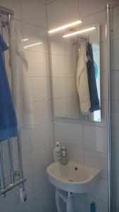 a white bathroom with a sink and a mirror at Ljust boende, egen ingång och trädgård i centrum in Varberg