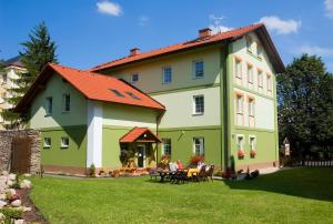 a green and white house with a table in the yard at Pension Marathon in Vrchlabí