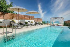 una piscina con sedie e ombrelloni in un edificio di Sabbia D`oro Beach Villa a Méson Yerakaríon
