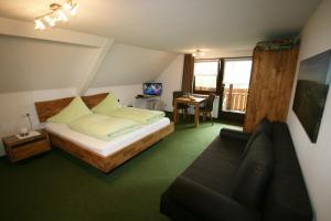 a bedroom with a bed and a couch and a desk at Café-Pension Feldbergblick in Titisee-Neustadt