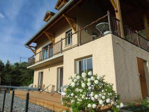 a building with a balcony and a bush with white flowers at La Villa 05 in Chorges