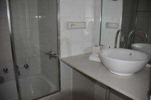 a white bathroom with a sink and a shower at Accommodation Sydney Studio with balcony apartment in Sydney