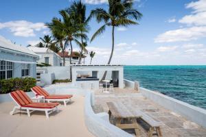 a house on the beach with chairs and the ocean at Water's Edge Villa - Oceanfront with Private Pool in Nassau