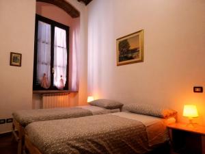 dwa łóżka w pokoju z oknem w obiekcie La casa di Giosuè w mieście Livorno