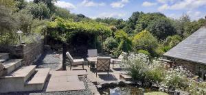 a garden with a table and chairs and a pond at Witherhill Granary in High Bickington