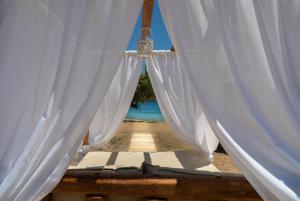 a bed with white curtains and a view of a pool at Alexandros by the Beach - Serifos in Livadakia