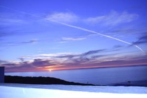 un rastro de avión en el cielo sobre el océano en Villa Athina, en Ambrami