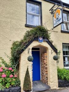 a building with a blue door and flowers at The Ship Inn in Bardsea
