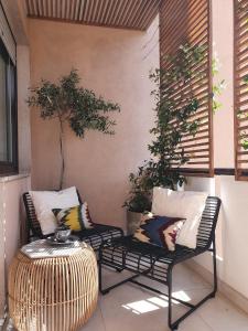 two chairs and a table on a porch with pillows at THE MIRROR GUESTHOUSE - TERME MERANO in Merano