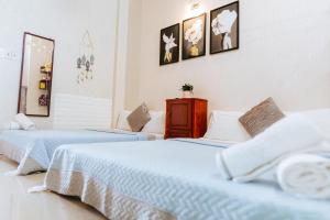 2 łóżka w pokoju z białymi ścianami w obiekcie Kota's House Homestay w mieście Hue