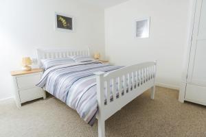 a white bedroom with a white bed and a night stand at Clyde View B&B in Dunoon