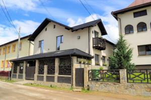 a large white house with a fence in front of it at Black Valley House in Gura Humorului