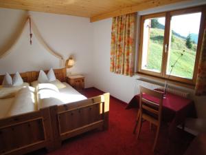 een slaapkamer met 2 bedden, een tafel en een raam bij Appartements Birkenhof in Lech am Arlberg