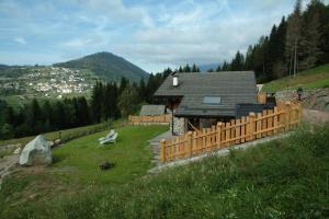 a house on a hill with a wooden fence at BAITA NONNO GHINO in Bedollo