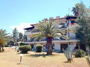 a building with a palm tree in front of it at Penny's Holiday Studio in Hanioti