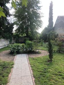 una pasarela en un jardín con flores y árboles en A la Fleur de Lys, en Langeais