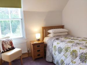 a bedroom with a bed and a chair and a window at Penbont House in Rhayader