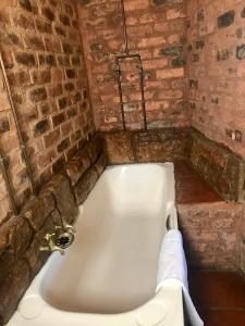 eine Badewanne in einem Zimmer mit Ziegelwand in der Unterkunft Old Transvaal Inn Accommodation in Dullstroom