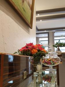 a table topped with a vase filled with flowers at Hotel Restaurant Le Dauphin et Le Spa du Prieuré in Caen