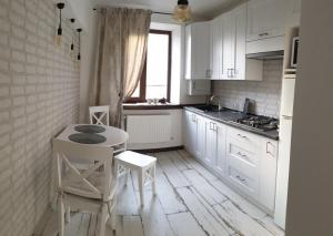 a kitchen with white cabinets and a table and chairs at Бажане місце in Kamianets-Podilskyi