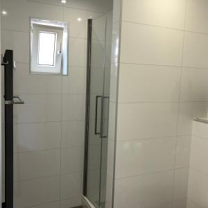 a shower with a glass door and a window at Zoutelande Koddelaan vakantiewoning in Zoutelande