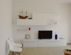 ein weißes Wohnzimmer mit einem TV und einem weißen Stuhl in der Unterkunft el Capitan de Mar in Chioggia