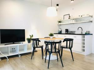 a kitchen with a table and chairs and a tv at Apartamenty Marynarska 2 in Rowy