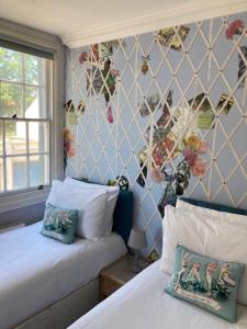 a bedroom with two beds and a wall with flowers at Parisien Parfumerie in Brighton & Hove