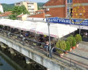 a restaurant with white awnings next to a river at Zlatna Ribica in Golubac