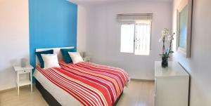 a bedroom with a bed with a colorful striped blanket at Frente al mar 1ª línea de playa in Conil de la Frontera