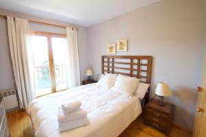 1 dormitorio con 1 cama con sábanas blancas y ventana en La Caseta de la Devesa, en Saga 